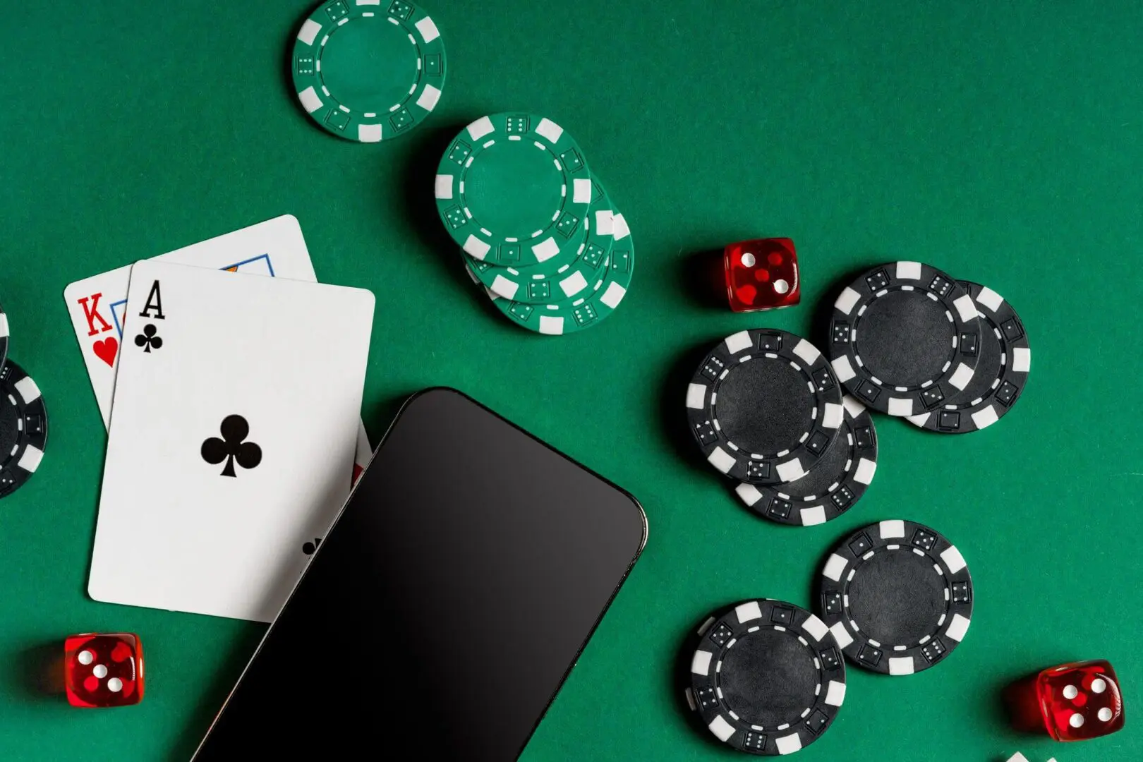Poker chips, cards, dice, and smartphone on table.